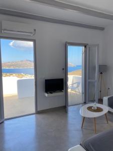 a living room with a television and a room with a view of the ocean at Maganiotis Rooms in Kimolos