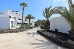 a street with palm trees and white buildings at Casa Louise in Costa Teguise