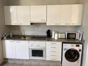 コスタ・テギセにあるCasa Louiseのキッチン(白いキャビネット、洗濯機付)