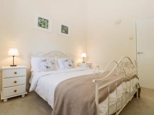 ein weißes Schlafzimmer mit einem weißen Bett und zwei Lampen in der Unterkunft Swallow Cottage in Shaftesbury