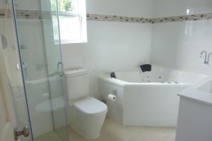 a white bathroom with a toilet and a bath tub at Charles Reuben Estate in Hobart