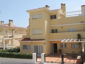 a large yellow building with a fence in front of it at ACOGEDOR ADOSADO entre mar y montaña in Cullera