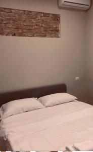 una camera da letto con un letto con lenzuola bianche e un muro di mattoni di Casa del Cuore a Reggio di Calabria