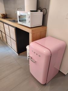 a pink refrigerator in a kitchen with a microwave at Dormi Tranquillo in Bologna +3 photos