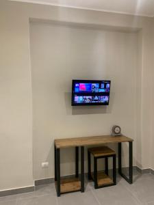 a tv on a wall with a table and a stool at Casa del Cuore in Reggio di Calabria