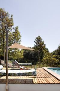 a wooden deck with an umbrella and chairs next to a pool at Casa do Vagar in Vimieiro