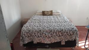 a bed with a black and white comforter and pillows at Pousada Cisne Branco in Natal