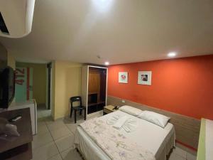 a bedroom with a bed with an orange wall at Rede Andrade Plaza Recife in Recife