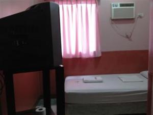 a room with a tv and a bed and a window at GV Hotel - Camiguin in Mambajao