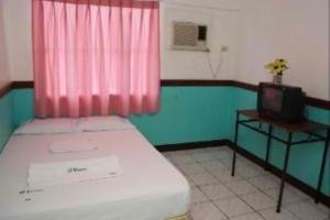 a small room with a bed and a television at GV Hotel - Camiguin in Mambajao