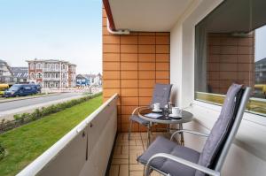 einen Balkon mit 2 Stühlen, einem Tisch und einem Fenster in der Unterkunft Seepferdchen in Westerland