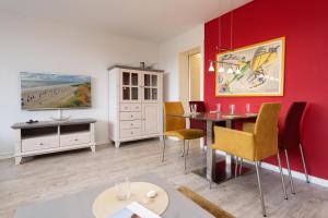 ein Esszimmer mit einer roten Wand sowie einem Tisch und Stühlen in der Unterkunft Seepferdchen in Westerland