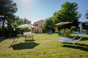 a yard with chairs and tables and umbrellas at Agriturismo Conero in Ancona