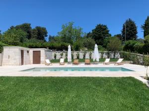 a pool with chairs and umbrellas in a yard at Trulli d'Itria in Martina Franca