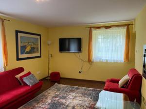 salon z czerwonymi meblami i telewizorem z płaskim ekranem w obiekcie Apartament Plaża z 2 sypialniami i salonem - 150 m od morza w Kołobrzegu