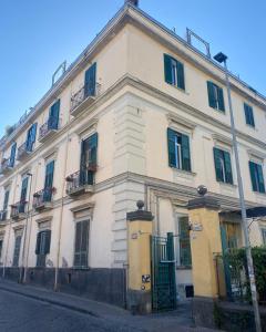 een groot wit gebouw met groene deuren en ramen bij Villa Sorge Apartments in San Giorgio a Cremano