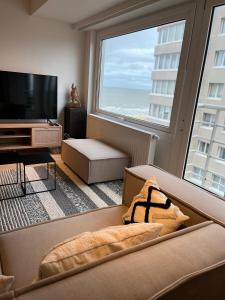 ein Wohnzimmer mit einem Sofa und einem großen Fenster in der Unterkunft Chez Coceau - Luxery apartment with sea view in Ostende