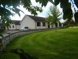 ein Haus mit einem Zaun und einem Auto im Hof in der Unterkunft Manorview B&B in Cookstown