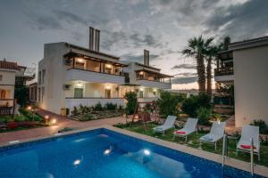 a villa with a swimming pool in front of a house at Corinthian Village in Vrachati