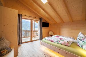 a bedroom with a bed and a large window at Bergchalet Heidi und Peter in San Leonardo in Passiria