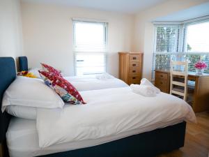 1 dormitorio con 2 camas con sábanas y almohadas blancas en Ellingham Apartments, Bordeaux Harbour, Guernsey en Vale