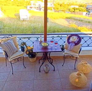 a table and chairs on a balcony with wine glasses at Family Home Myrina Lemnos in Myrina