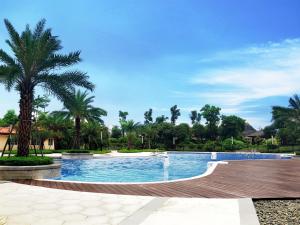 a swimming pool in a resort with palm trees at Ramada Plaza Liuzhou Liudong in Liuzhou