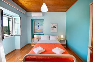 a bedroom with a bed with an orange blanket at Sterna House Paxos in Vlachopoulátika