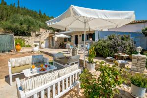 a patio with a table and an umbrella at Sterna House Paxos in Vlachopoulátika