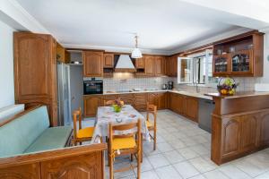 a kitchen with wooden cabinets and a table and chairs at Sterna House Paxos in Vlachopoulátika +16 photos