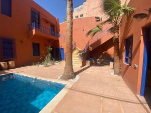 a swimming pool in front of a house with palm trees at Comfy Colonial Apartments in Marrakech