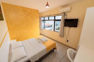 a hotel room with a bed and a television at Pousada Terra do Sol Natal in Natal