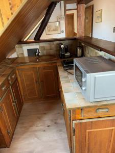 une cuisine avec des armoires en bois et un micro-ondes sur un comptoir dans l'établissement Top Floor Apartment with Mountain Views in the centre of Argeles Gazost, à Argelès-Gazost