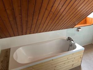 La salle de bains est pourvue d'une baignoire et d'un plafond en bois. dans l'établissement Top Floor Apartment with Mountain Views in the centre of Argeles Gazost, à Argelès-Gazost