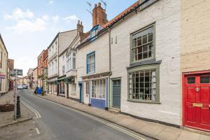 una calle vacía con edificios blancos y puertas rojas en 48 High Street, en Bridlington