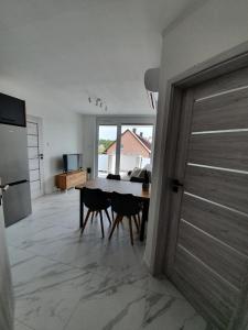 eine Küche und ein Esszimmer mit einem Tisch und einer Tür in der Unterkunft Mierzeja Park 13 apartament 40m2 in Sztutowo