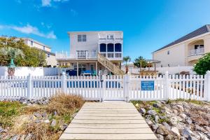 a white fence with a wooden walkway in front of a house at A Slice of Paradise in Virginia Beach