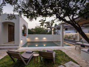 a backyard with a pool and two chairs and a table at Rastoni home - Rethimno, Crete - Enjoy your slow-travel mindset in Áyios Yeóryios