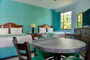 a room with two beds and a table and chairs at Coco La Palm in Negril