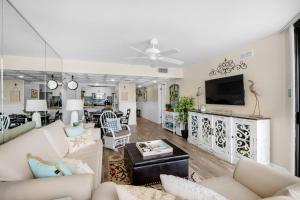 a living room with white furniture and a flat screen tv at Windward 403 at Edgewater in Panama City Beach