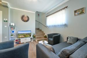 a living room with two couches and a tv at CVETKOVA HIŽA sa JACUZZIJEM in Tuheljske Toplice