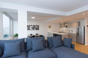 a living room with a blue couch and a kitchen at Pacifico Departamentos in Ushuaia