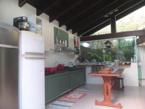 a kitchen with a refrigerator and a table in it at Pousada Ares do Sul in Penha