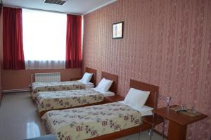 a room with two beds and a table and a window at Hotel Albatros in Irkutsk