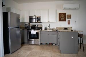 una cocina con electrodomésticos de acero inoxidable y armarios blancos en Pet Friendly! Private retreat in Nob Hill, en Albuquerque