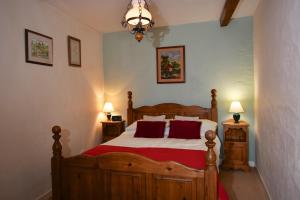 Un dormitorio con una gran cama de madera con almohadas rojas en Glascoed Farmhouse, en Carmarthen
