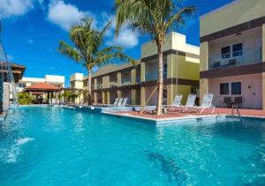 une piscine avec des palmiers et un bâtiment dans l'établissement Apartamento Vacacional en Aruba Cerca a la Playa, à Palm-Eagle Beach