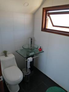 Un baño con inodoro y lavabo de cristal. en Casa COSMOS golf., en Algarrobo