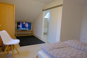 a bedroom with a bed and a tv and a chair at Ferienweingut Wissing Wohnung Frieda in Gleiszellen-Gleishorbach