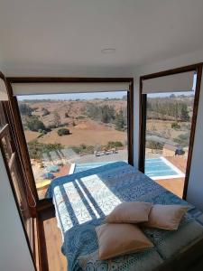 a bedroom with a bed and a large window at Casa COSMOS golf. in Algarrobo